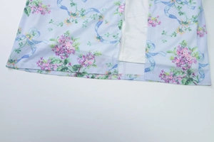 Detail of slit hem and white lining on floral backless summer slip dress with blue ribbon print