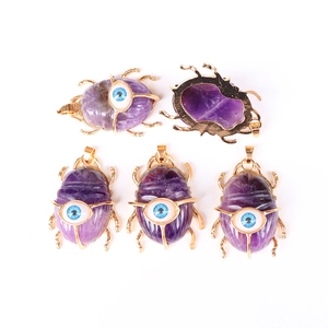 Detailed front and back view of gold-rimmed amethyst scarab pendants with blue eye detail