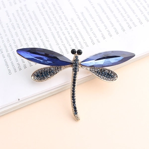 Detailed close-up of a blue dragonfly brooch with crystal wings on an open book