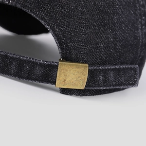 Detail of adjustable metal buckle and vintage bronze fastener on black denim baseball cap