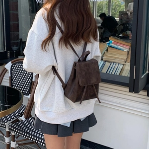 Zaino vintage in pelle PU marrone con coulisse mostrato su una modella in un caffè all'aperto