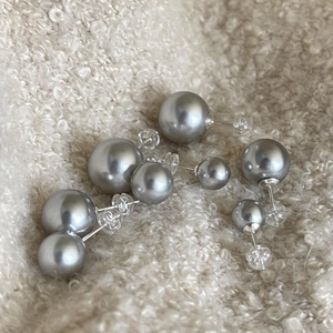 Macro detail of gray pearl earrings in multiple sizes on a soft beige fabric