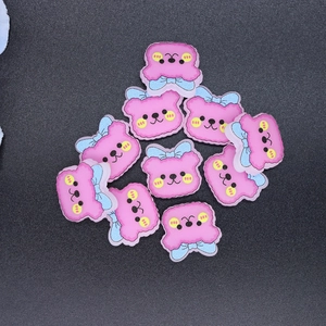 Flat lay of small pink resin cartoon bears with blue bows for DIY phone case crafts