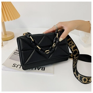 Detail of black leather crossbody bag with triangle quilting and gold chain strap
