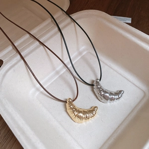 Detail view of gold and silver croissant pendants with realistic textures on cord necklaces