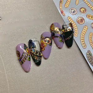 Détail d'autocollants pour ongles baroques avec chaînes dorées, fleurs et perles de nacre