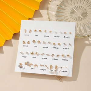 Detail view of 20-pair gold earring set with pearls and rhinestones on a white display card
