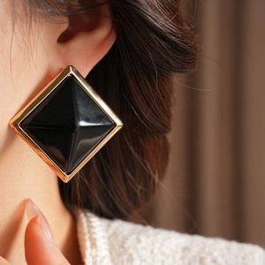 Close-up of geometric resin square stud earrings with gold metal frame on model ear