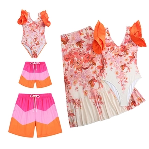 Flat lay of family swimwear set with floral ruffles and V-pattern beach shorts