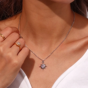 Model wearing a silver star necklace with pink stone and golden diamond flower rings