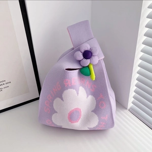 Close-up of lilac knitted knot handbag with white flower pattern and plush floral charm