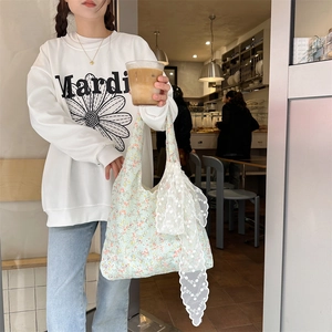 Detailed close-up of a floral canvas tote bag featuring a large white lace bow accent