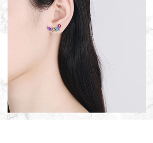 Close-up of vibrant multi-colored zircon ear studs in a curved cluster on ear