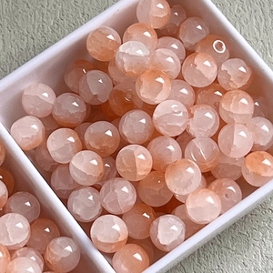 Macro view of translucent orange 10mm ice-cracked glass beads in a white tray
