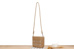 Détail du sac en papier tissé main avec perles décoratives sur fond en bois