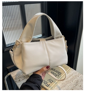 Detail of lychee textured leather shoulder bag in cream with golden hardware accents