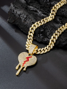Close-up of gold iced-out Cuban link chain with a sparkling red lightning broken heart pendant