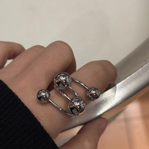 Detail of silver spherical stainless steel ring featuring four metallic beads on model hand