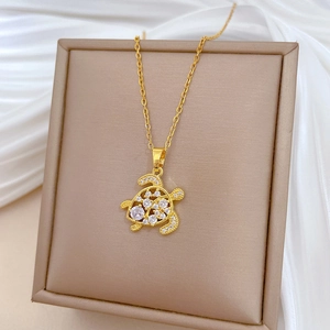Macro shot of gold turtle pendant with clear crystals on beige jewelry box lid