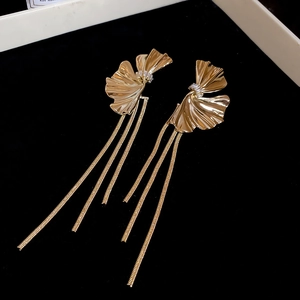 Detail view of gold tassel earrings with fan leaf design and sparkling white stones