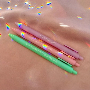 Detail of three funny matte pens in purple, pink, and green with sassy white slogans