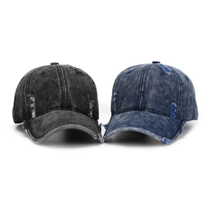 Close-up of distressed vintage denim baseball caps with frayed holes and worn texture