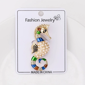 Macro shot of cartoon seahorse brooch with colorful enamel, faux pearls and crystals