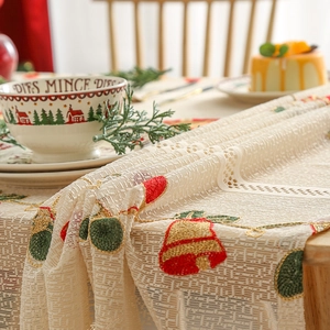 Beige lace Christmas table runner with festive bell embroidery on a cozy holiday dining table