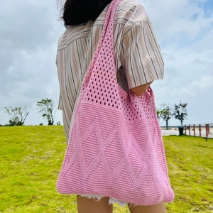 Pink hand-knit tote bag with diamond pattern shown in an outdoor lifestyle setting