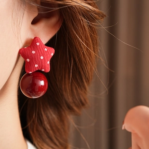 Close-up of red polka dot star fabric earrings with pearl drop on female model