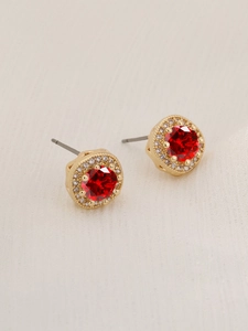 Macro detail of round red crystal earrings with gold finish and halo diamond setting