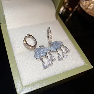 Close-up of blue crystal cloud earrings with transparent teardrop zircon pendants in a box