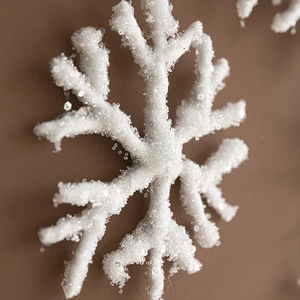 White 3D Christmas snowflake ornament with sparkling sequins on a warm brown background