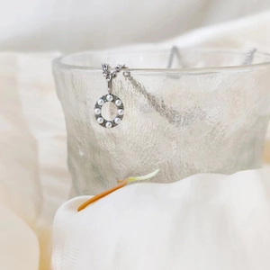 Close-up of pearl-encrusted letter O pendant on a silver-tone necklace chain