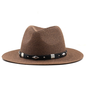 Gros plan d'un chapeau de paille marron avec bandeau en cuir noir et clous métalliques