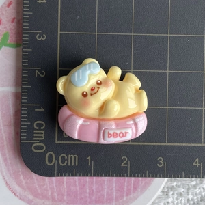 Detailed scale view of a 2.5cm yellow bear resin charm on a pink swim ring