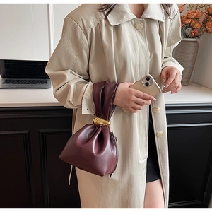 Detail view of burgundy leather cloud bag featuring an elegant gold metal knot handle