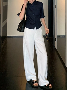 Détail du cintrage de la chemise en lin bleu marine et pantalon blanc à taille haute
