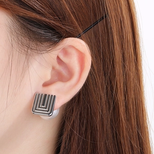 Close-up of French vintage silver square earrings with stripes and pearl backings