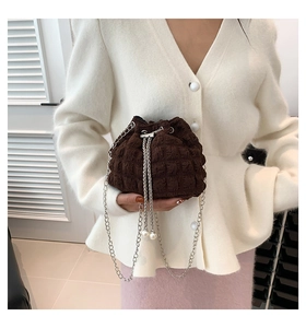Close-up of brown pleated bucket bag with metal chain strap and decorative pearl charm