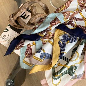 Detail of silk-like square scarf featuring geometric horsebit and chain patterns