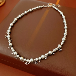 Detailed view of grey beaded pearl necklace with silver metal charms and lobster clasp