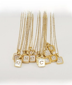 Macro view of square 18K gold plated stainless steel letter pendants with shell inlay