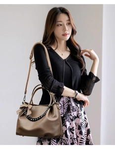 Detail of brown leather tote bag with bow decoration and black woven chain strap