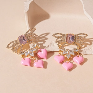 Macro detail of bow earrings featuring pink zircon hearts and sparkling crystal stones