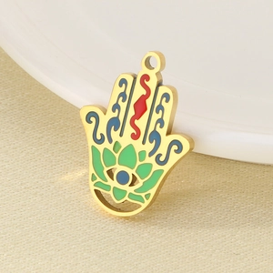 Macro shot of 18K gold Hamsa hand pendant with vibrant red, blue and green enamel details