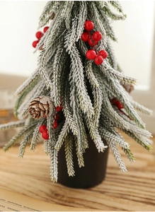 Close-up of mini PE Christmas tree with white flocking snow, red berries and pinecone