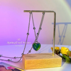 Detail of color-changing heart pendant on a silver ball chain against purple light