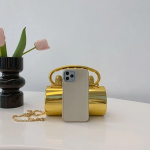 Detailed macro view of golden cylindrical evening clutch with lion head relief and chain