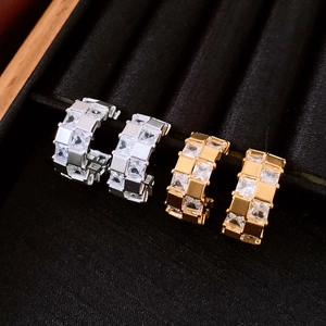 Détail macro de boucles d'oreilles géométriques plaquées or et argent avec cristaux clairs